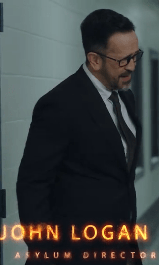 A man in a suit and glasses walking in a hallway, with the text 'JOHN LOGAN ASYLUM DIRECTOR' at the bottom.