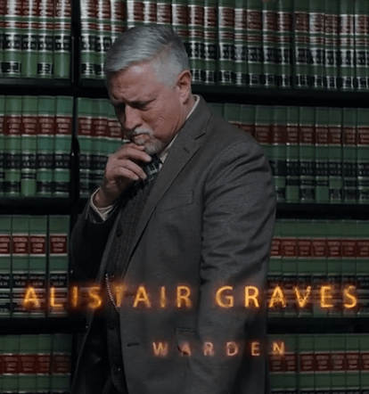 A middle-aged man with gray hair and a thoughtful expression stands in front of a large bookshelf filled with law books. The text 'ALISTAIR GRAVES' and 'WARDEN' overlay the image.